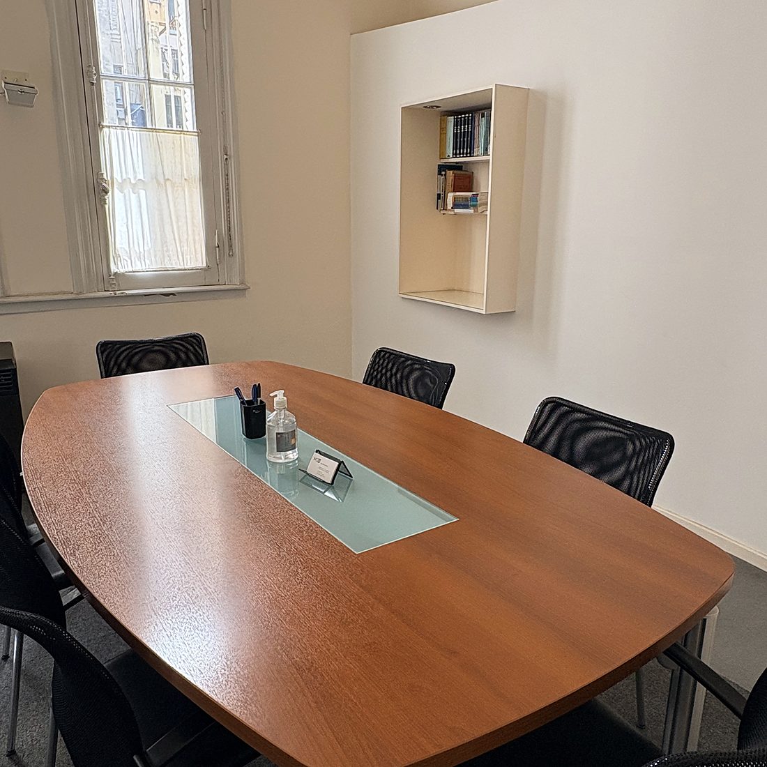 Sala de firmas de la escribanía: la mesa ovalada, las sillas y la biblioteca